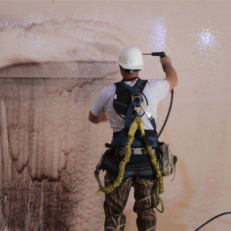 A worker cleaning the inside of a water tank.